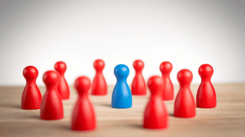 Group of red game pieces, surrounding a blue game piece, representing collective punishment