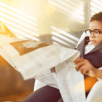 Young kid reading large newspaper