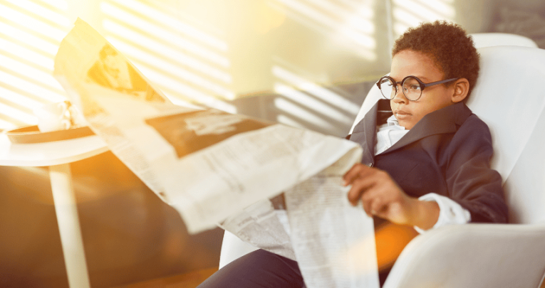 Young kid reading large newspaper