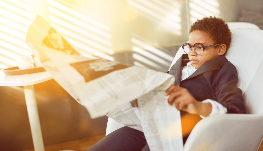 Young kid reading large newspaper