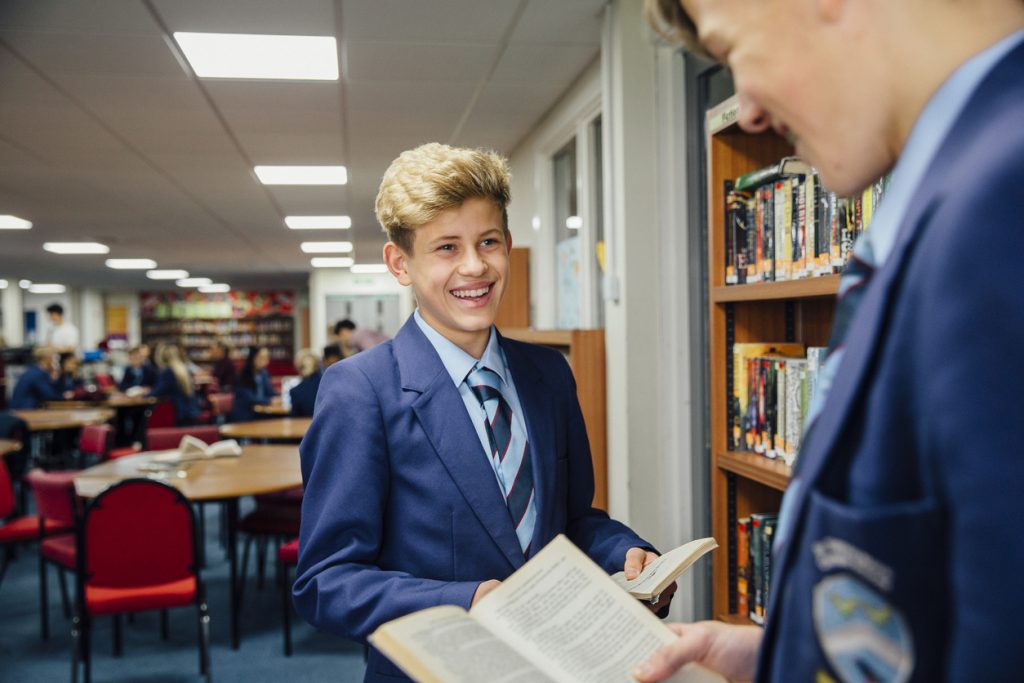 Two schoolboys smiling in library