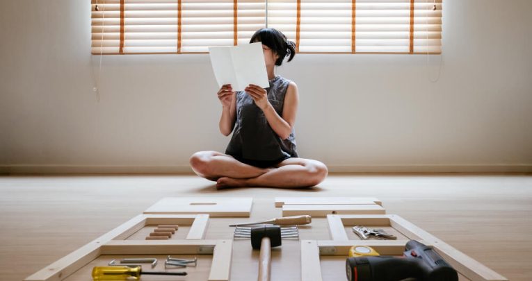 Woman looking at flatpack furniture instructions, representing instructional writing