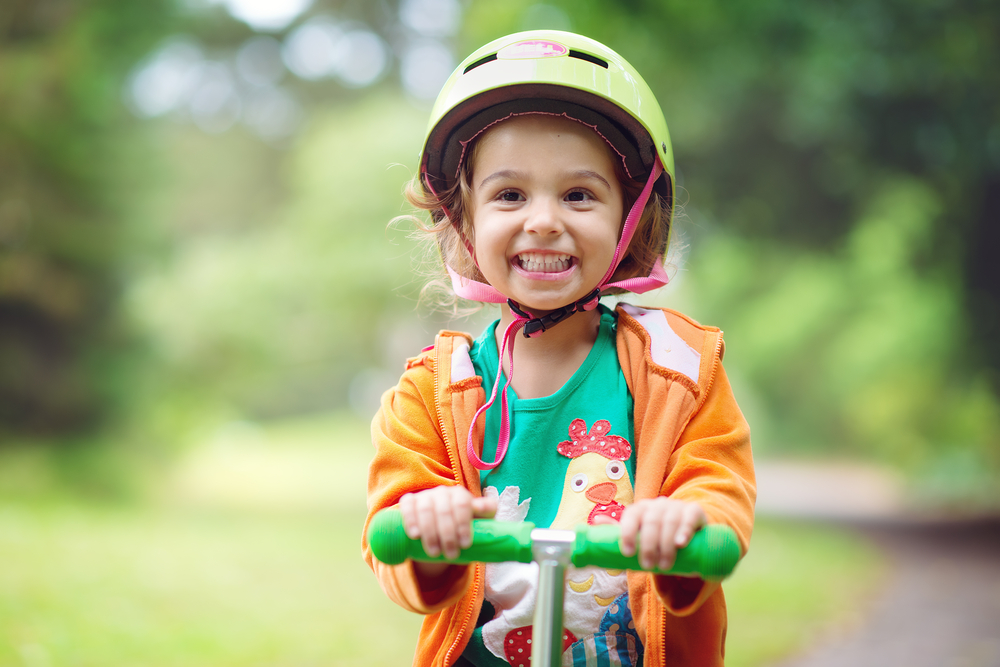 Kid on scooter with helmet, representing Child Safety Week