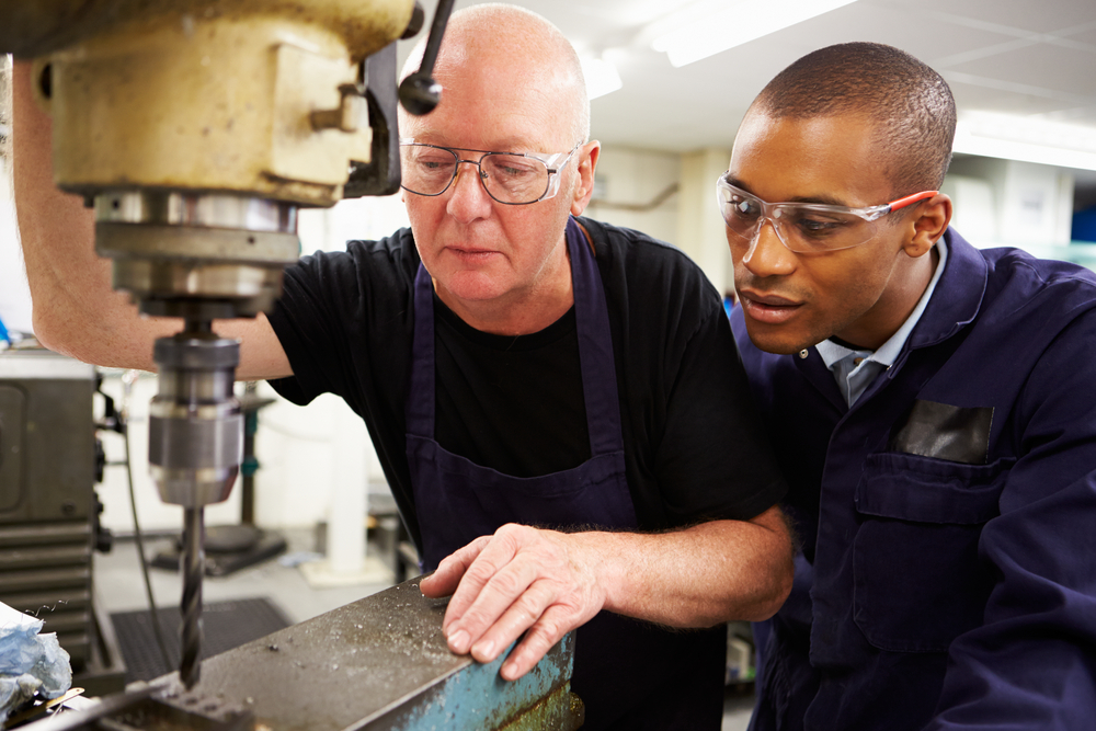 Apprentice looking over shoulder of engineer, representing National Apprenticeship Week