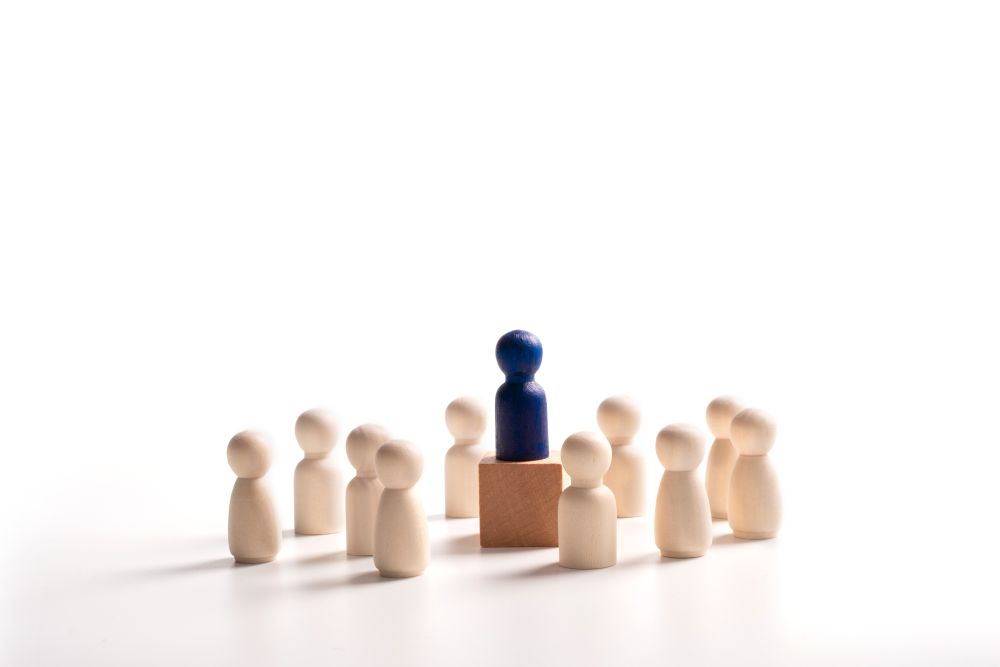 One wooden figure standing on a block, surrounded by other wooden figures, representing behaviour management strategies for primary school