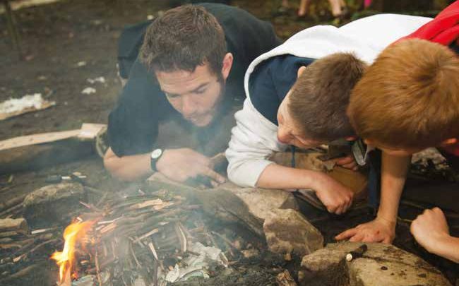 Kids lighting a fire on a residential trip for schools