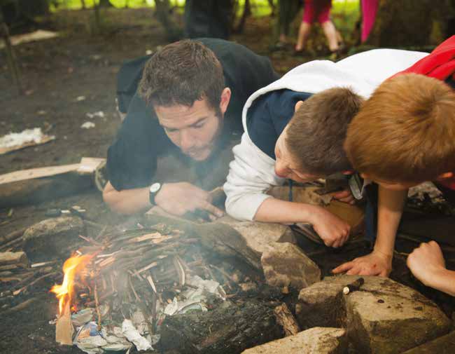 Kids lighting a fire on a residential trip for schools
