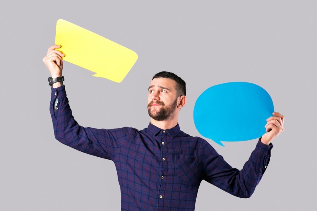 Teacher holding up two paper speech bubbles, representing oracy