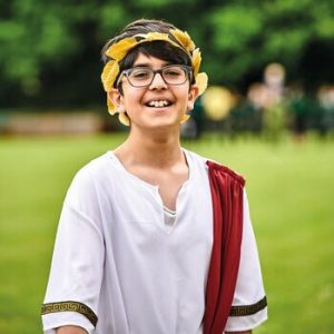 Boy in white tabard and gold crown smiling