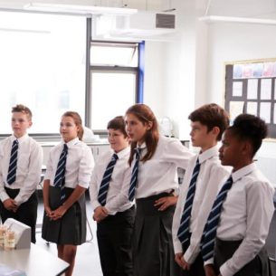 School science class watching a demonstration being given by their teacher