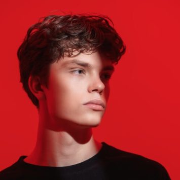 Sullen-looking boy against red background