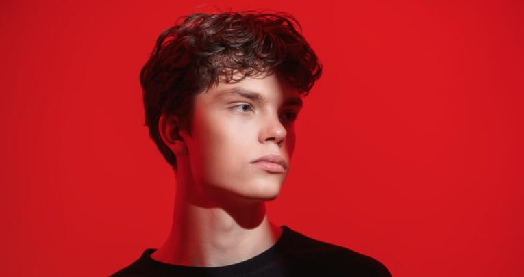 Sullen-looking boy against red background