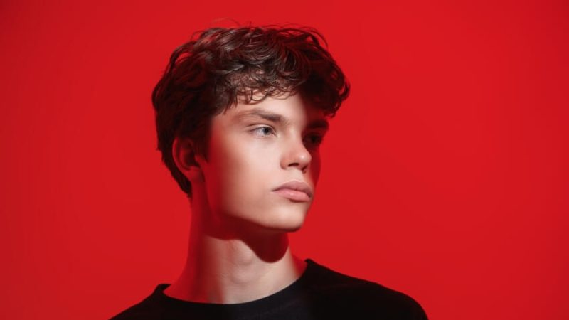 Sullen-looking boy against red background