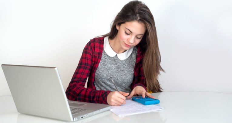 Teenage girl using a laptop and calculator