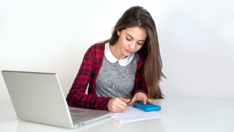 Teenage girl using a laptop and calculator