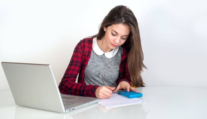 Teenage girl using a laptop and calculator