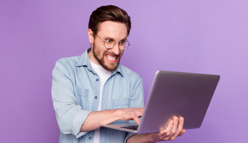 Angry adult man holding laptop and typing