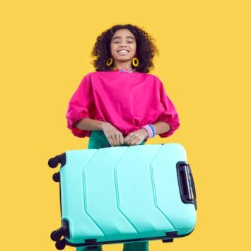 Excited teenage girl carrying a suitcase, ahead of going on an international school trip