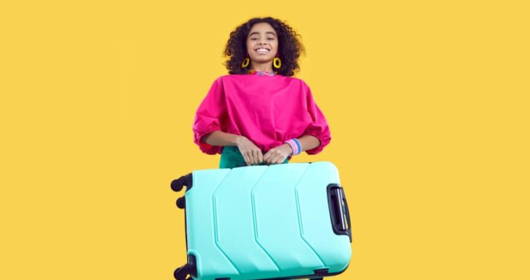 Excited teenage girl carrying a suitcase, ahead of going on an international school trip