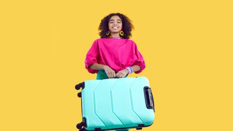 Excited teenage girl carrying a suitcase, ahead of going on an international school trip