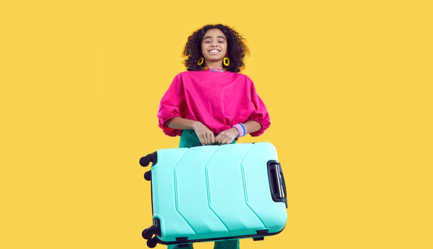 Excited teenage girl carrying a suitcase, ahead of going on an international school trip