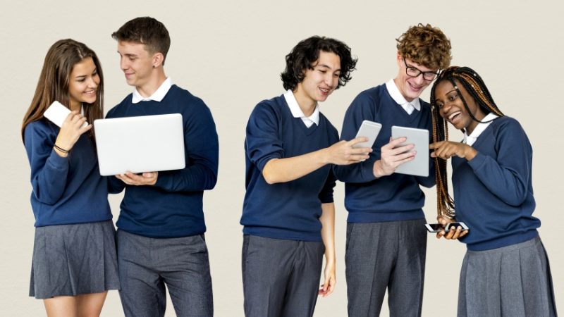 group of school students using laptops and tablets