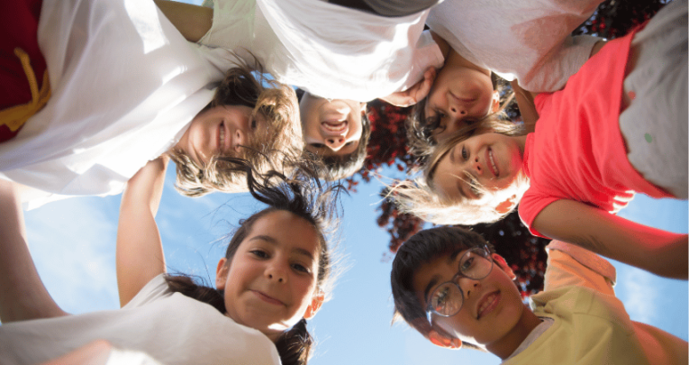 Children in a circle looking happy during Anti Bulllying Week