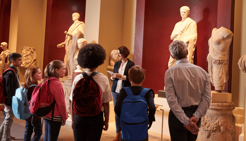 School trips image of children in a museum, listening to teacher