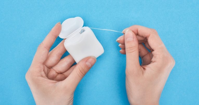 close-up on someone pulling dental floss out of a container