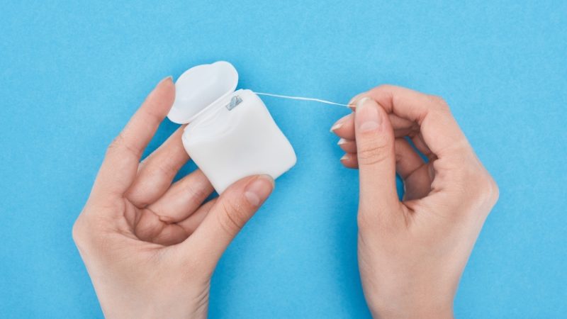 close-up on someone pulling dental floss out of a container