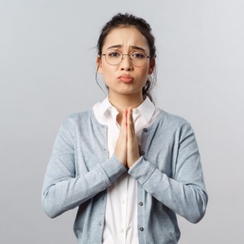 Photo of a female teacher with hands clasped and a pleading expression