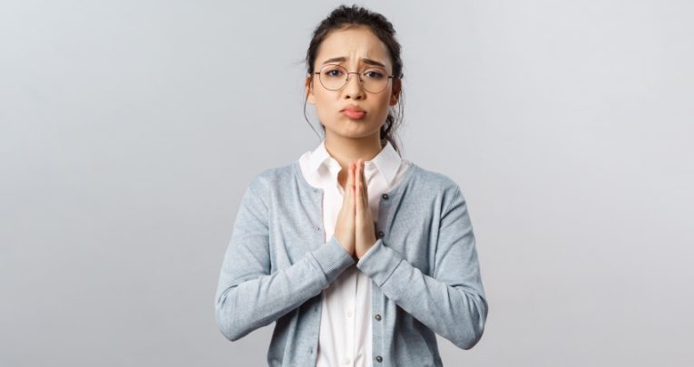 Photo of a female teacher with hands clasped and a pleading expression