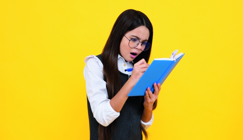 Photo of young teenager looking surprised as she writes in a notebook