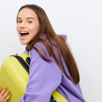 Photo of excited teenage girl carrying a suitcase