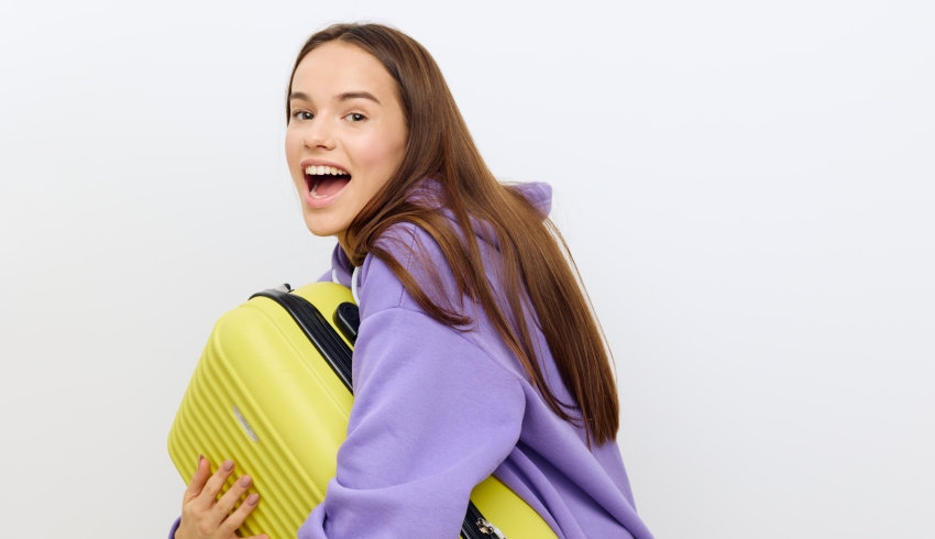 Photo of excited teenage girl carrying a suitcase