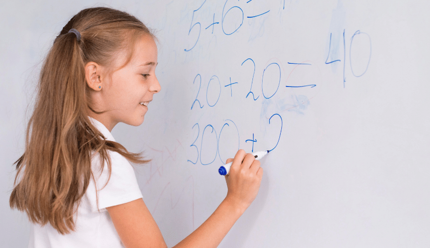 Child writing sums on whiteboard