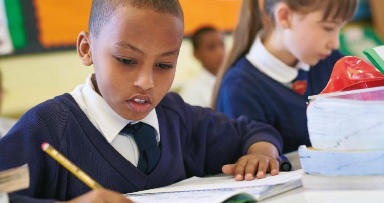 Boy in school uniform writing in book