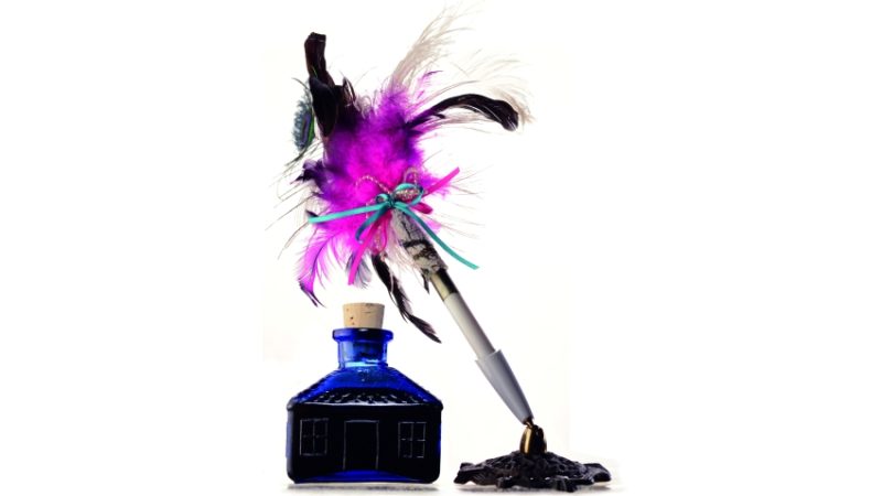 close-up photograph of a quill and an ink bottle
