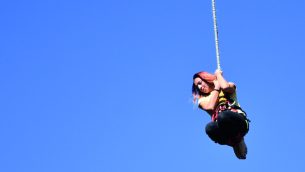 photograph of teenage girl hanging from a bungee rope