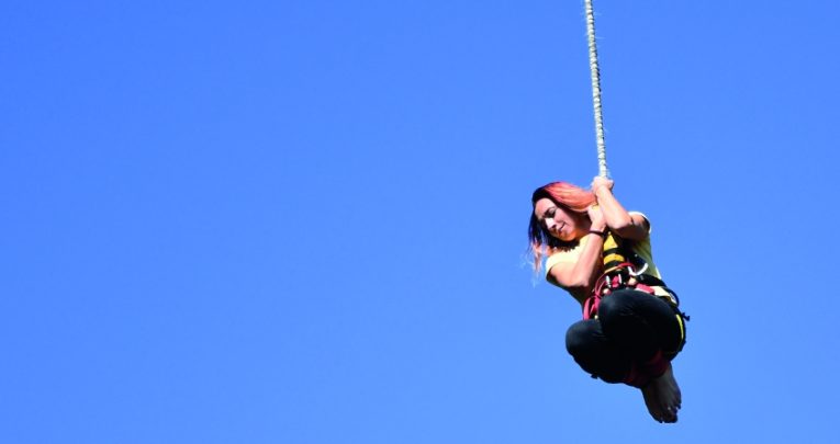 photograph of teenage girl hanging from a bungee rope