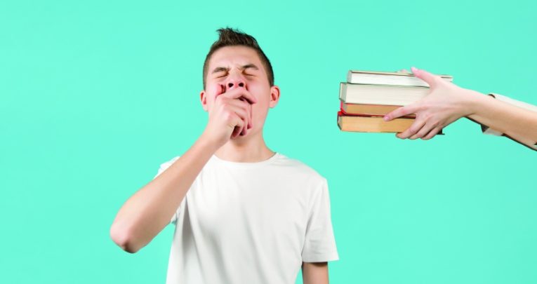 Photograph of a yawning boy being offered a selection of books