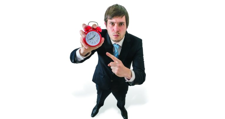 Comical photo of irritated, besuited man holding an alarm clock