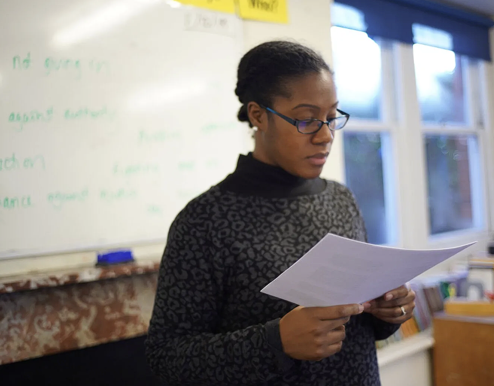 Teacher in classroom looking at paper resource