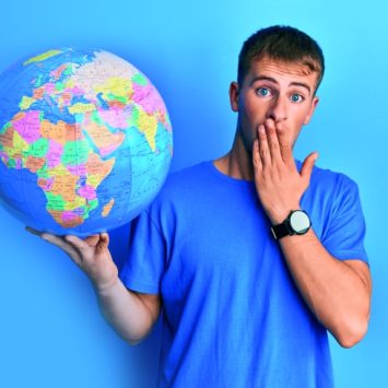 photo of teenage boy with a shocked expression holding up a model globe