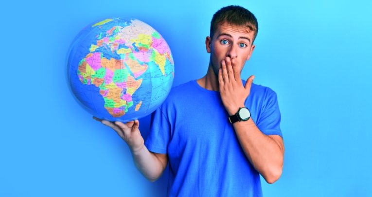 photo of teenage boy with a shocked expression holding up a model globe