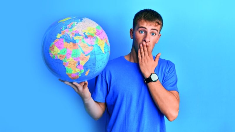 photo of teenage boy with a shocked expression holding up a model globe