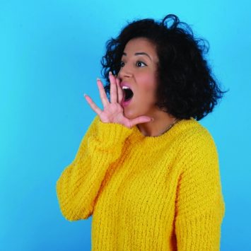 Photo of woman cupping hand around her mouth and shouting loudly