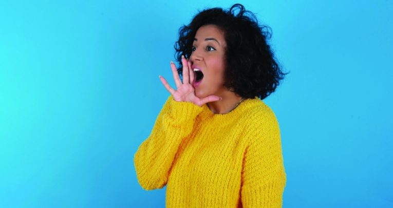Photo of woman cupping hand around her mouth and shouting loudly