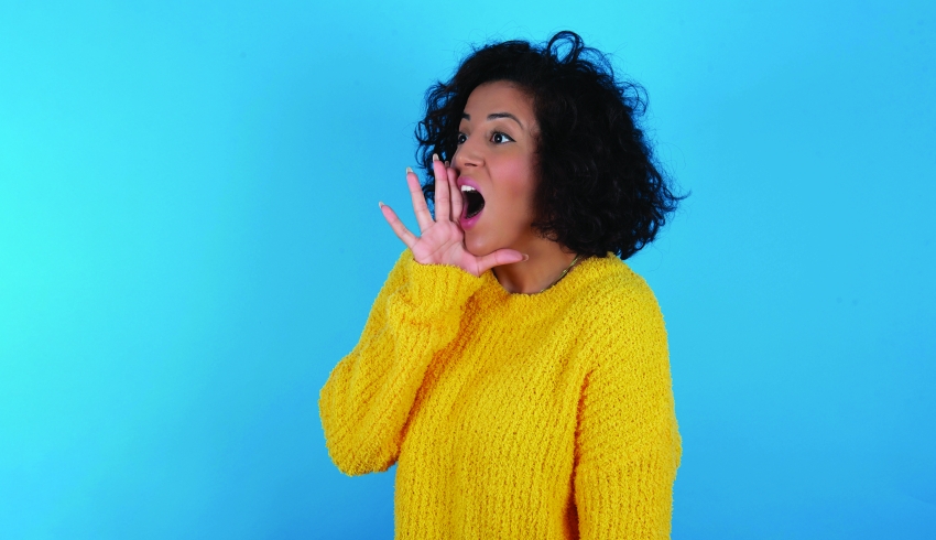 Photo of woman cupping hand around her mouth and shouting loudly