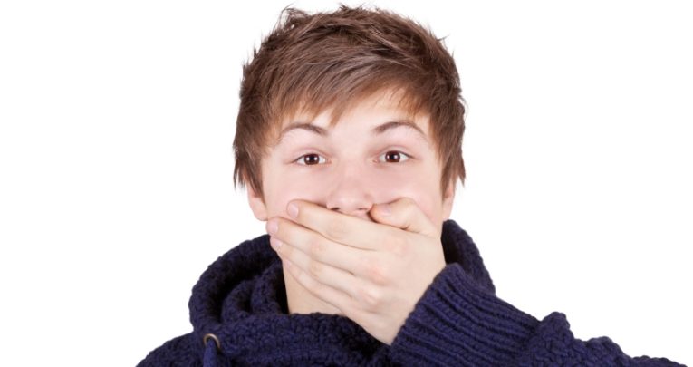 Photo of a teenage boy with his hand over his mouth